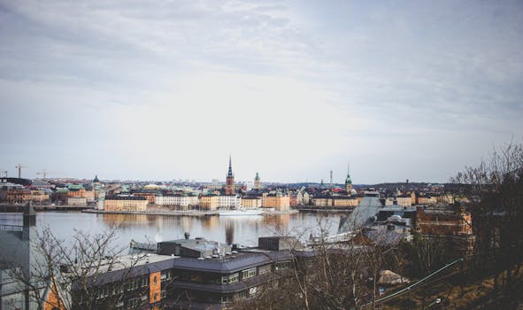 pexels-photo-1529040-1529040 Aerial view of Stockholm's historic skyline reflecting across the river under a cloudy sky.